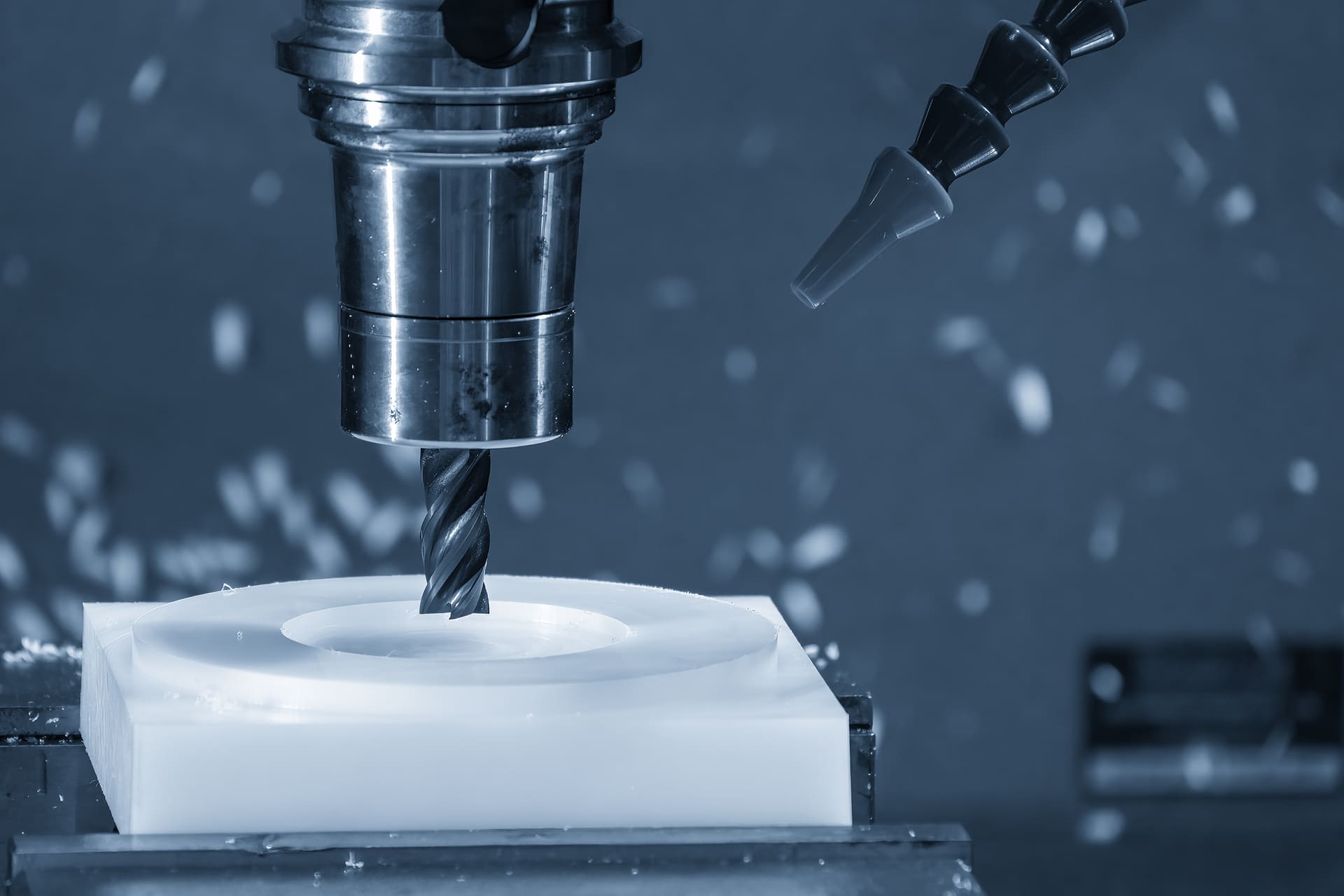 CNC-Fräsen und Nacharbeit Nahaufnahme einer CNC-Fräse beim mechanischen Nacharbeiten eines weißen Kunststoffteils in der Produktion.