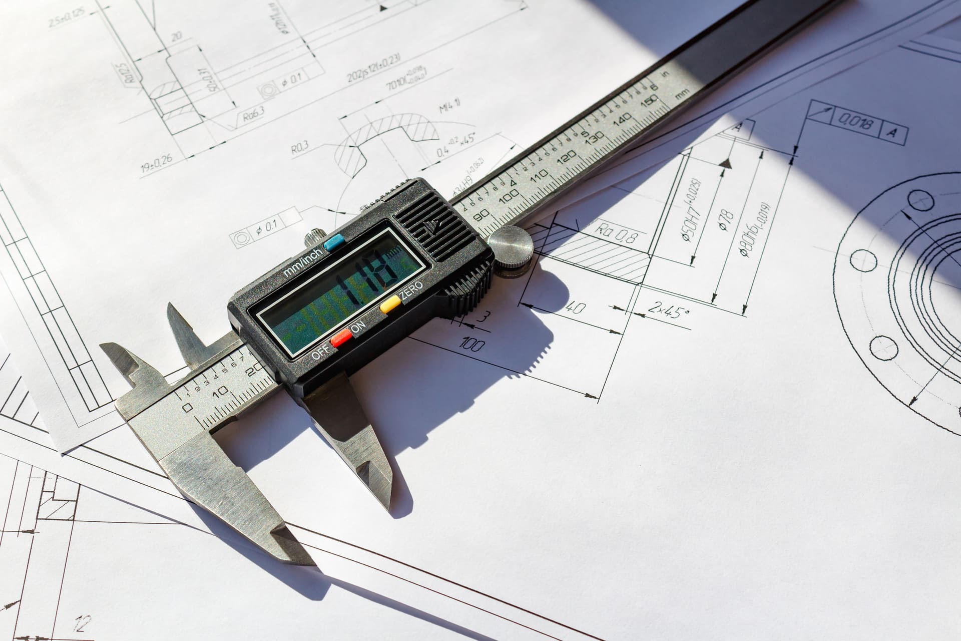 Qualitätskontrolle mit Messschieber Nahaufnahme eines digitalen Messschiebers, der auf einer technischen Zeichnung liegt, um die Qualität von Bauteilen zu überprüfen.